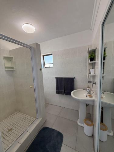 a white bathroom with a shower and a sink at Lilies & Leopards B&B in Mossel Bay