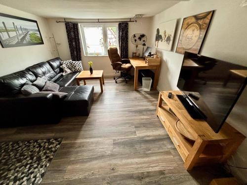 a living room with a black leather couch and a piano at Kleiner Kalle in Melsungen