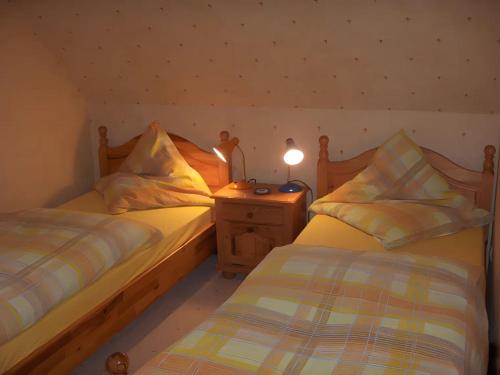 a bedroom with two beds and a night stand with a lamp at Fewo Nordseeblick in Langeneß