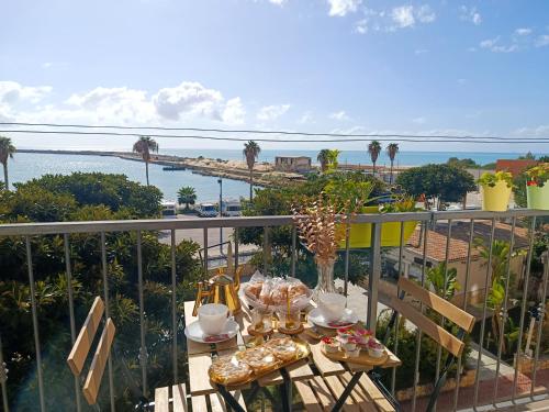 une table sur un balcon avec vue sur l'océan dans l'établissement Vacanze Mariu', à Porto Empedocle