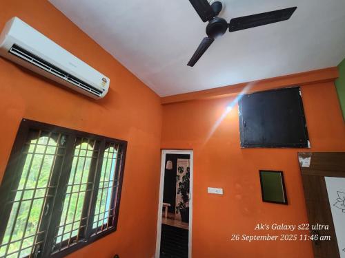 a room with an orange wall with a ceiling fan at Le homestay villa in Puducherry