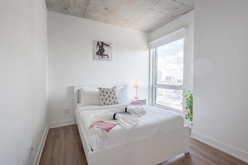 een witte slaapkamer met een bed en een raam bij Downtown Montreal 1BR - Sleeps 4 in Montreal