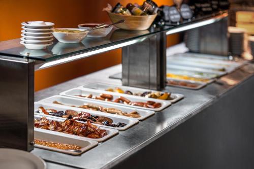 a buffet line with trays of food on it at Clarion Congress Hotel Olomouc in Olomouc