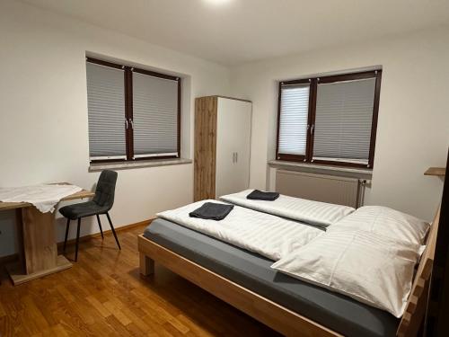 une chambre avec un lit et un bureau et deux fenêtres dans l'établissement Golf und Thermen Ferienhaus Golfblick Bad Loipersdorf, à Gillersdorf