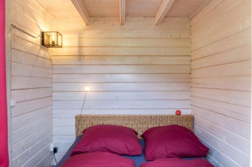 a small room with a bed with two red pillows at Sundowner Cabin in Oberammergau
