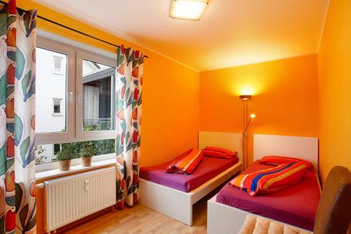 two beds in a room with orange walls and a window at Fewo am Hennesee in Meschede