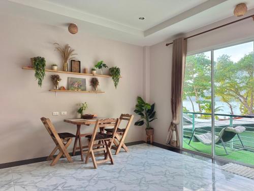 a dining room with a table and chairs and a balcony at Sea Dreamer Beachfront Apartments in Phuket