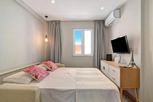 Cette chambre comprend un lit avec des oreillers roses et une télévision. dans l'établissement Casa Rebelo da Silva, à Faro