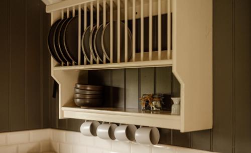 a kitchen with a shelf with plates and dishes at Shepherds Huts at Ballyness Farm in Dungiven