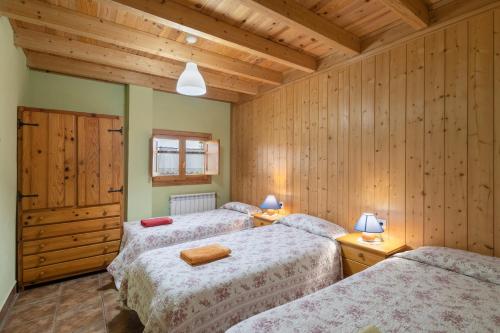 Dos camas en una habitación con paredes de madera. en Cal Panxeta, en Balsareny