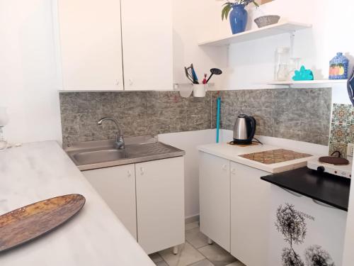a kitchen with white cabinets and a sink at Syrios Suites No 1 in Kalymnos