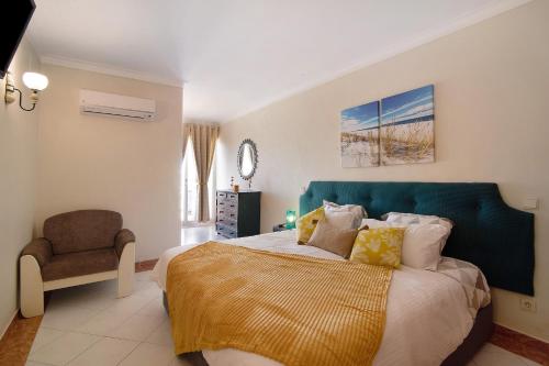 a bedroom with a bed with a blue headboard and a chair at Paradis Bleu in Albufeira
