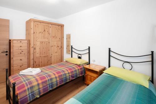PiaiaにあるAppartamento Rododendroのベッドルーム1室(ベッド2台、木製キャビネット付)