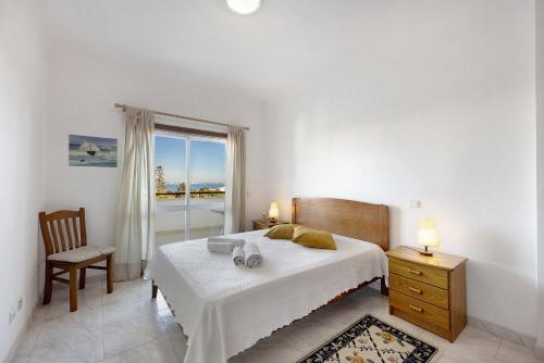 ラゴスにあるLagos Ocean View Apartmentのベッドと椅子と窓のある寝室