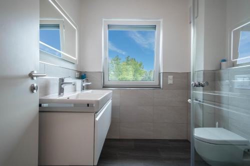 a bathroom with a sink and a toilet and a window at Ferienwohnung 1 am Biohof Eriskirch in Eriskirch