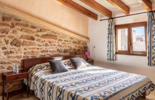 a bedroom with a bed and a stone wall at Casa Magui in Capdepera