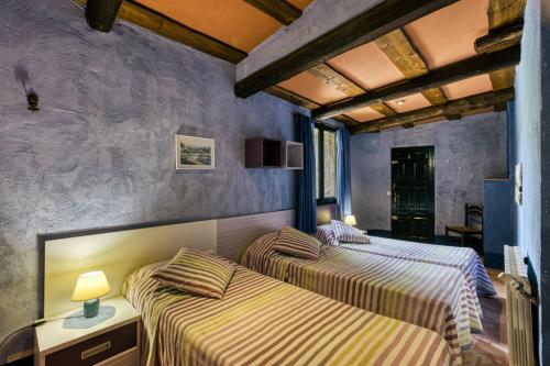 two beds in a room with purple walls at Cal Secretari Rural de Can Gat Vell in Llampaies