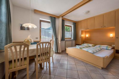 a bedroom with a bed and a table and chairs at App Sonne Nr 18 in Lutago