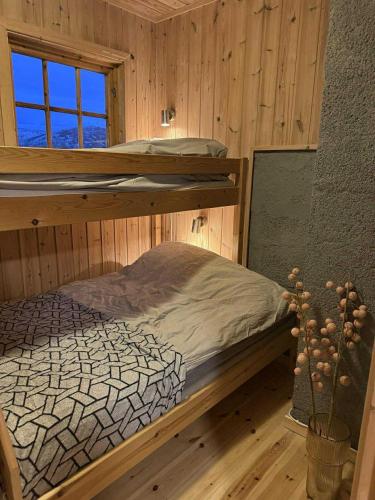 トロムソにあるNordic Retreatの木造キャビン内の二段ベッド付きのベッドルーム1室を利用します。