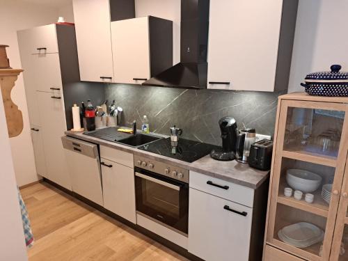 kuchnia z białymi szafkami i zlewem w obiekcie Somski Saalbach w Saalbach Hinterglemm