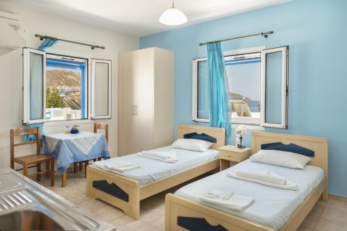 two beds in a room with two tables and windows at Studios Ninemia Serifos 4 in Livadion