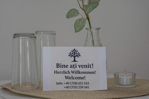 a sign on a table with a vase with a plant at Pensiunea Serenitas in Sebeşel