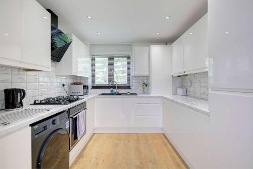 a white kitchen with a stove and a sink at Spacious & Bright 3 Bedroom House in Peterborough in Paston