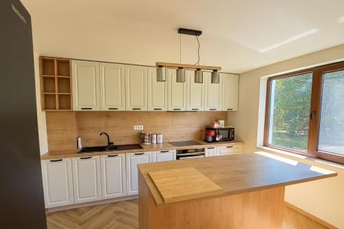 a kitchen with white cabinets and a wooden counter top at Transrarau Lodge in Pojorîta