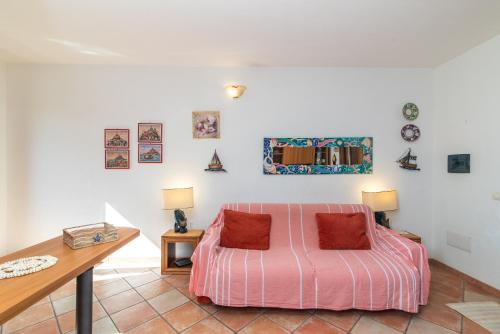 een slaapkamer met een roze bed en een bureau bij Appartamento I Lecci in San Teodoro