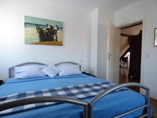 a bedroom with a blue bed and a painting on the wall at Ferienwohnung Lavendel in Sinzheim