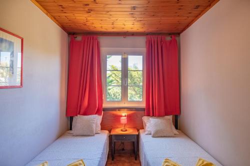 two beds in a room with red curtains and a window at Escalante C8 2 in Cala'n Bosch