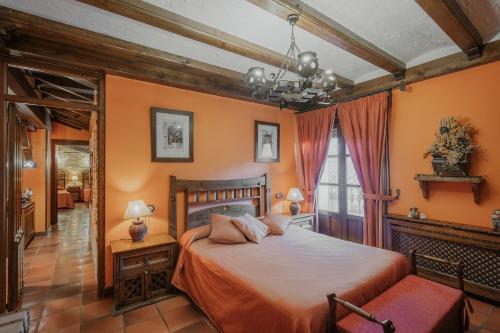 Un dormitorio con una cama grande con paredes naranjas. en Casa Rural Los Beatos, en Urueña
