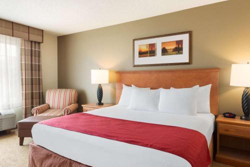a hotel room with a large bed and a chair at Country Inn & Suites by Radisson, Davenport - Quad Cities in Davenport