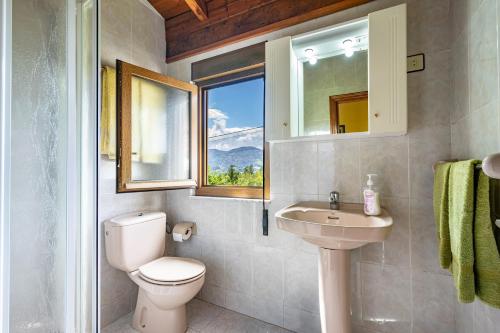a bathroom with a toilet and a sink and a window at La Casita de Heidi in Cangas de Onís