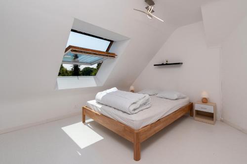 Una cama en una habitación blanca con ventana. en Maison avec piscine, en Kervignac