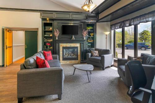 a living room with a fireplace and a tv at Black Bear Inn, an Ascend Collection Hotel in Orono