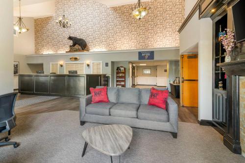 a living room with a gray couch and red pillows at Black Bear Inn, an Ascend Collection Hotel in Orono
