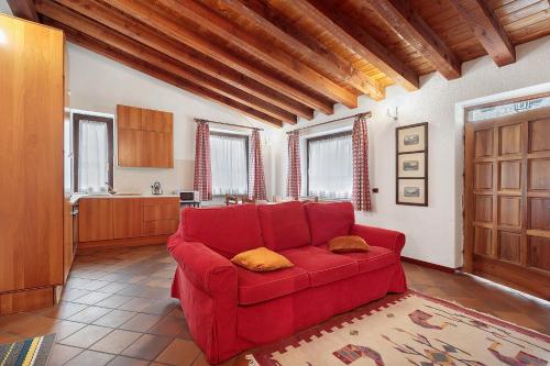ein rotes Sofa im Wohnzimmer mit Küche in der Unterkunft Au Petit Chevrot - Classic in Aosta