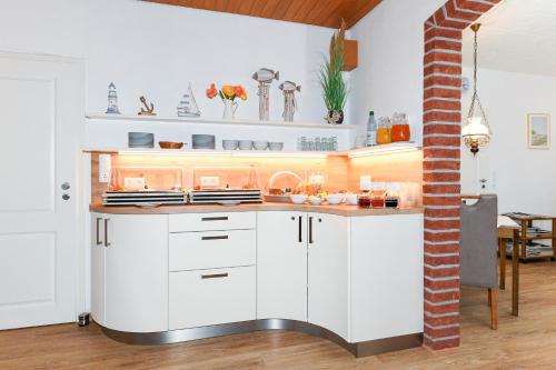 een keuken met witte kasten en een aanrecht bij Hotel-Pension Marlies in Neuharlingersiel