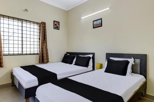 two twin beds in a room with a window at Super Hotel O Indian Residency, Near Adams Academy, Kadugodi in Bengaluru