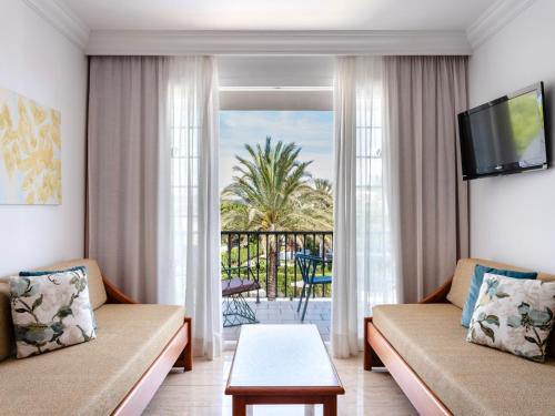 a living room with two couches and a balcony at Inturotel Sa Marina in Cala d´Or