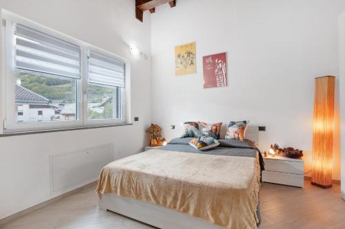 a white bedroom with a bed and a window at Villa Maffei in Aosta