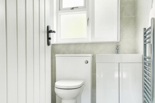 ein weißes Bad mit einem WC und einem Fenster in der Unterkunft 2 Bed - Sleeps 6 - Parking - Town Centre in Reigate
