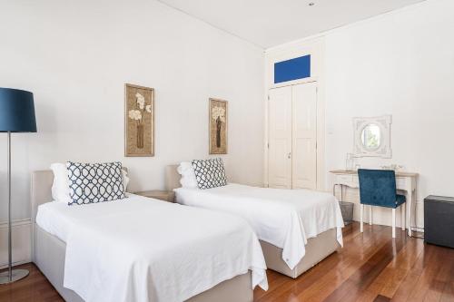 a white bedroom with two beds and a desk at GuestReady - Charming House Marquês in Porto