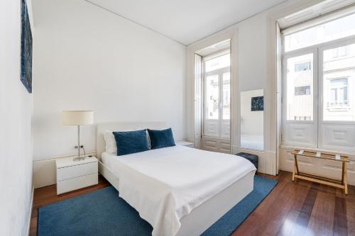 a white bedroom with a bed and two windows at GuestReady - Charming House Marquês in Porto