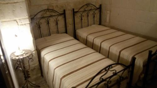 two twin beds in a room with a lamp at Antiche Corti in Scorrano