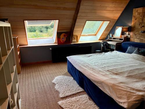 Un dormitorio con una cama y dos ventanas. en Villa Kerdrean, en Cléguérec