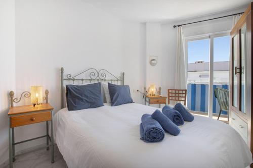 ein Schlafzimmer mit einem Bett mit blauen Kissen und einem Fenster in der Unterkunft Plata Ático in Torremolinos