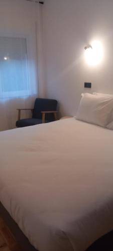 a bedroom with a white bed and a blue chair at Lavanda Termas de São Pedro do Sul in Termas de Sao Pedro do Sul