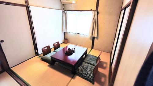a table and chairs in a room with a window at Wahori - A Traditional Japanese Guesthouse in Beppu